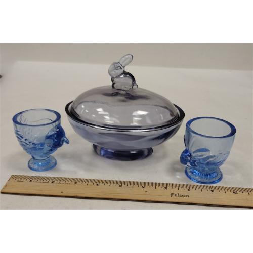 PURPLE GLASS LIDDED CANDY DISH WITH RABBIT FINIAL, TWO BLUE GLASS EGG CUPS WITH CHICK AND RABBIT